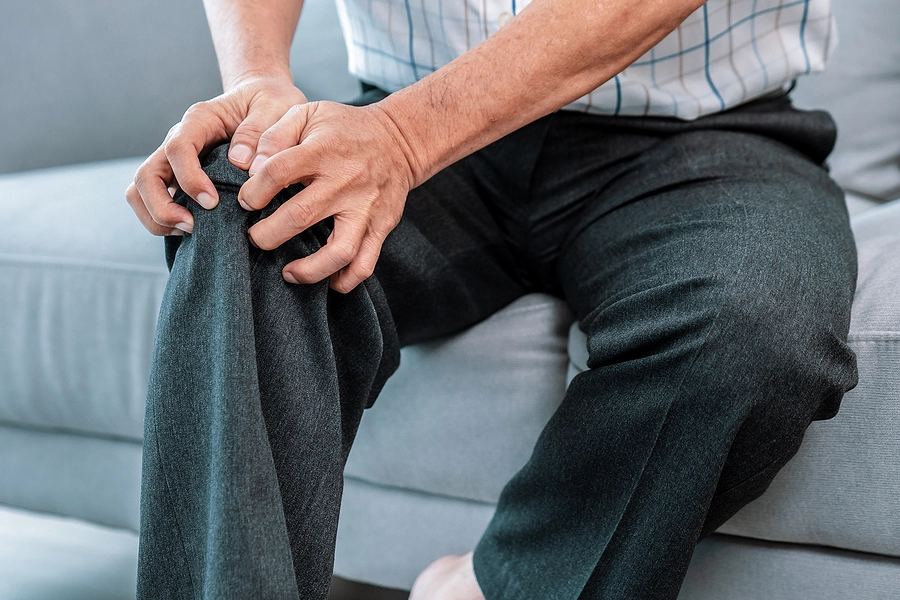 male veteran with secondary knee injury from a service connected condition sitting on the couch at home