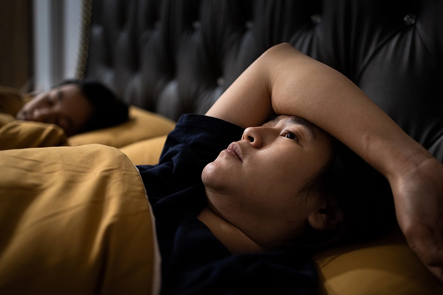 veteran with insomnia lying in bed awake while her partner sleeps