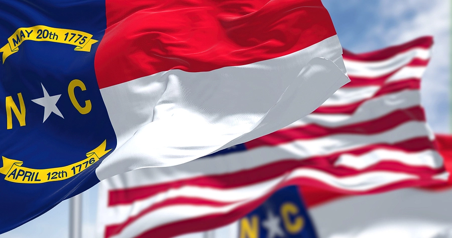 north carolina state flag flying next to the us flag outside a veteran health center